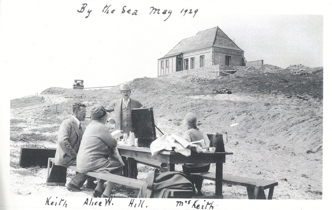 Archival photograph captioned By the Sea, May 1929, a picnic table on the bare dunes below the first cottage