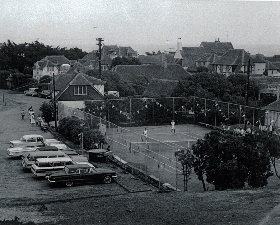 A tennis tournament on the community courts, pennants strung along the fence