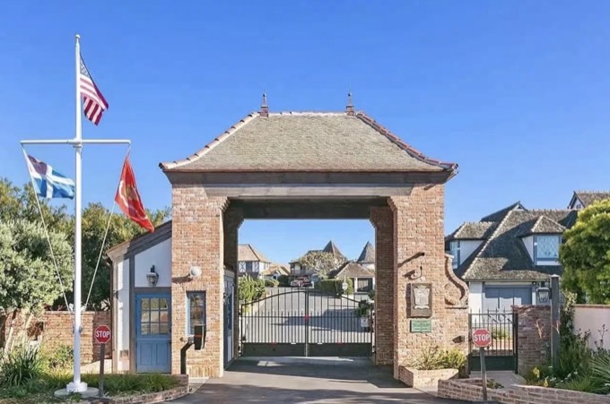 The brick St. Malo gatehouse under a blue sky, flags flying and the village beyond the arch
